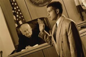 Male witness being sworn-in before judge (toned B&W)